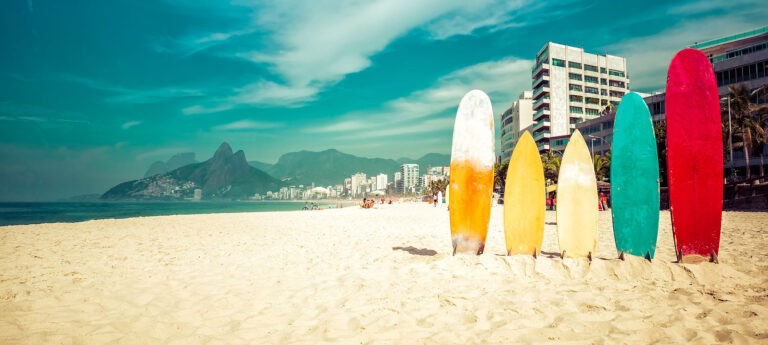 Bunte Surfbretter, die am Strand von Ipanema im Sand stecken.