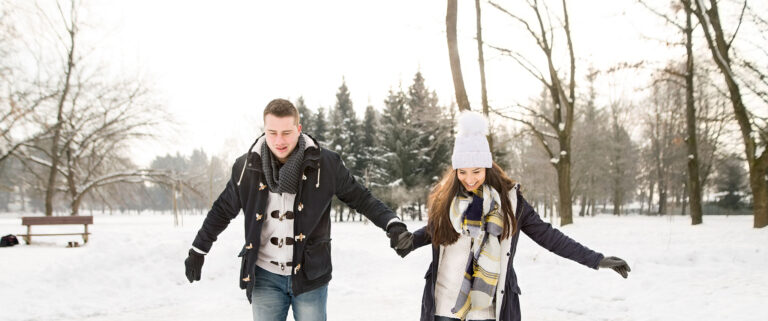 Ein warm gekleidetes Paar stapft durch den Schnee.