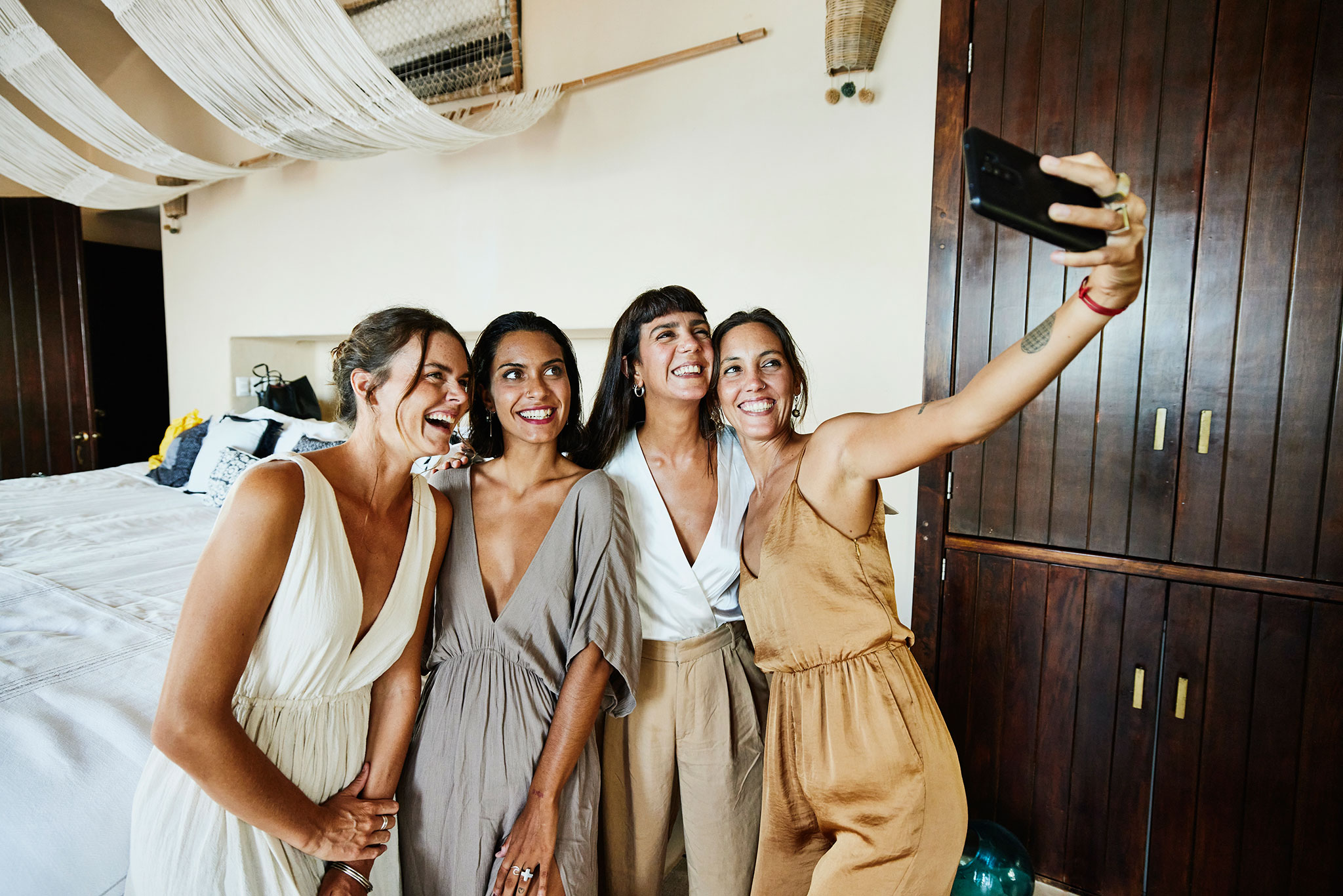 Vier Freundinnen posieren für ein Selfie in einer Luxushotelsuite vor einer Hochzeit.