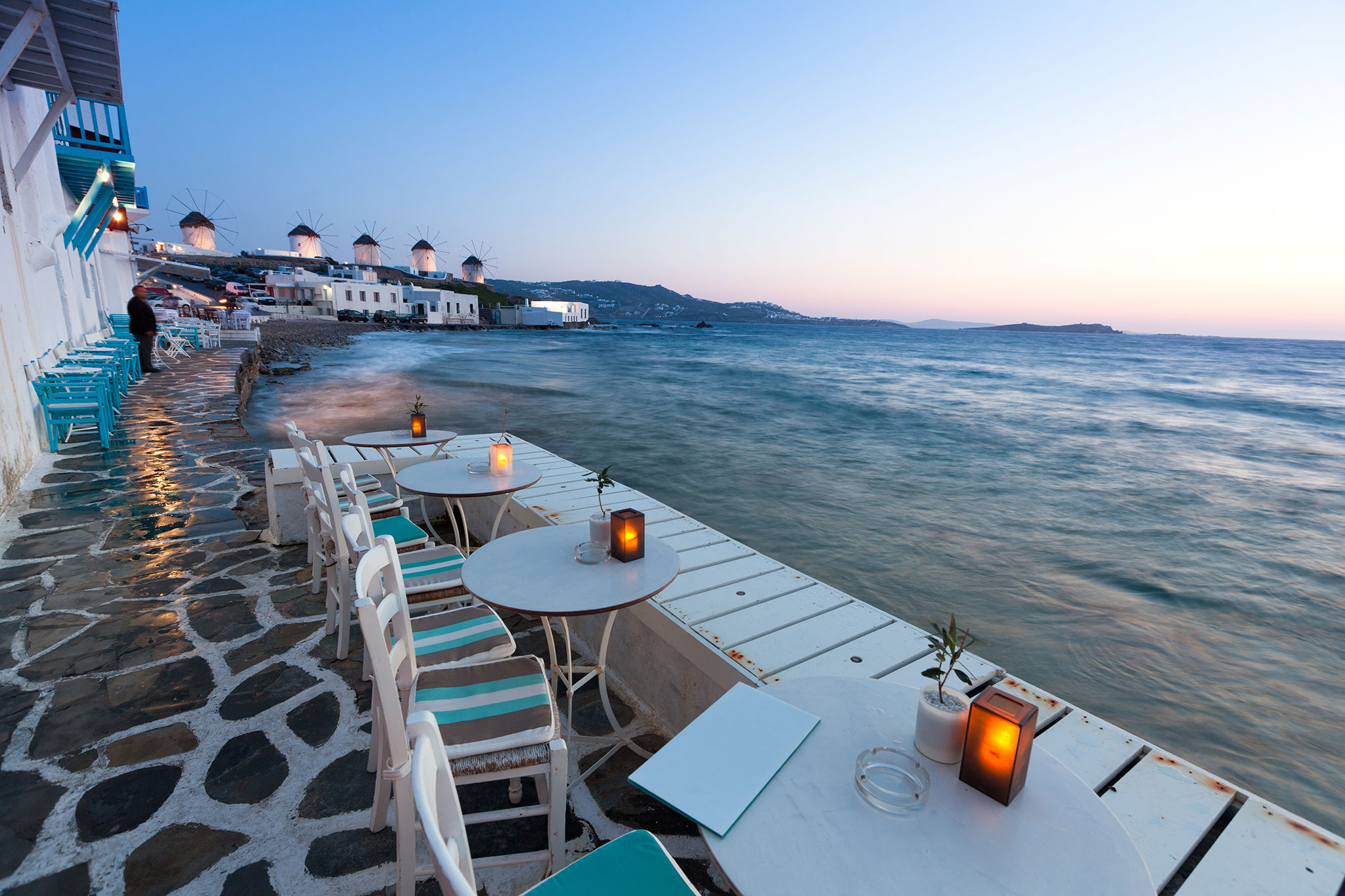 Tische und Stühle mit Blick auf das Mittelmeer in der Abenddämmerung auf Mykonos.