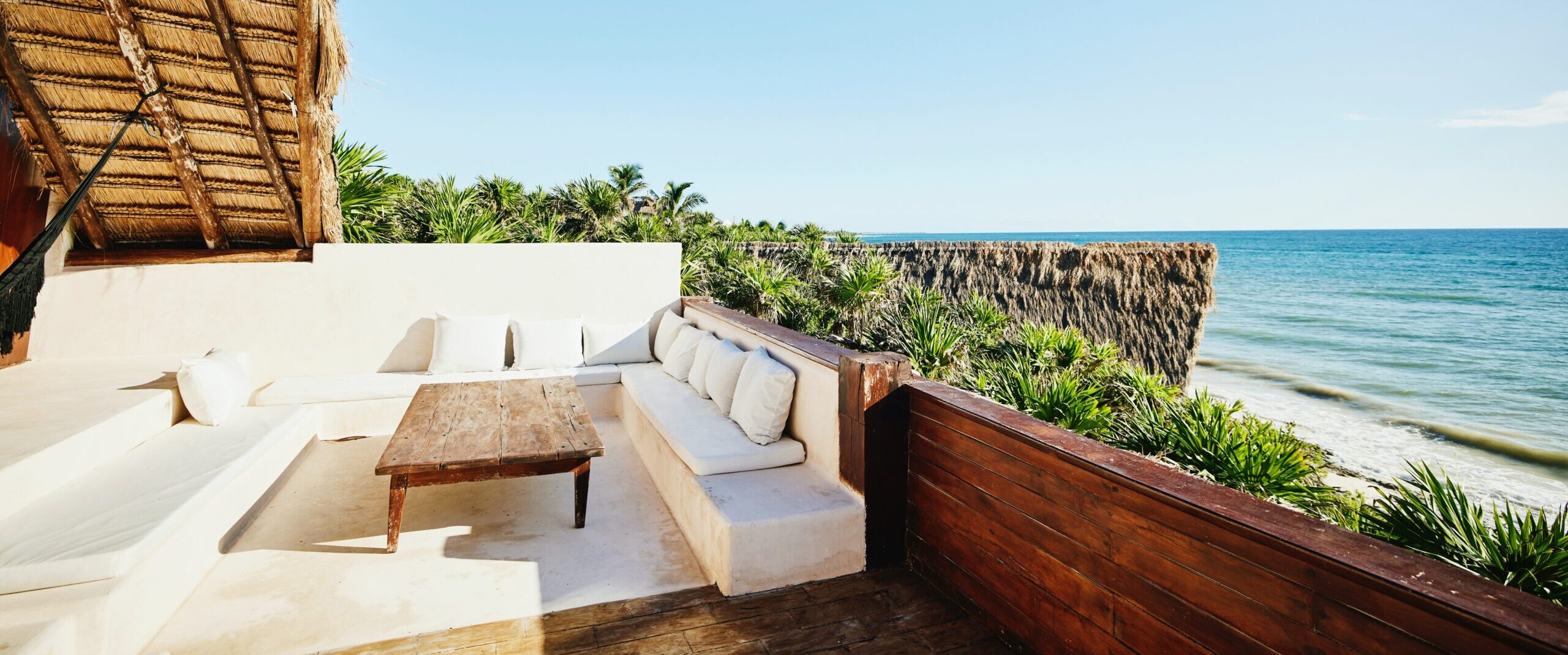 Weite Aufnahme einer Sitzecke auf dem Deck einer Luxussuite in einem tropischen Ferienort